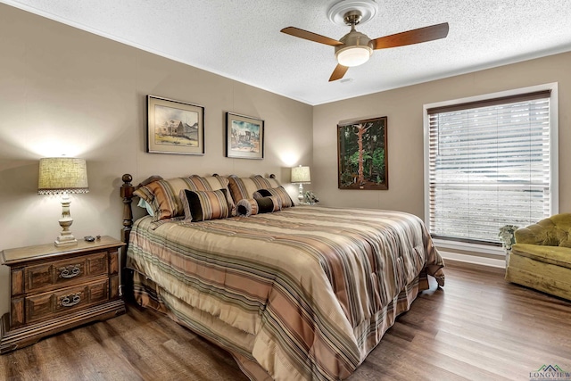 bedroom featuring ceiling fan, hardwood / wood-style floors, and a textured ceiling