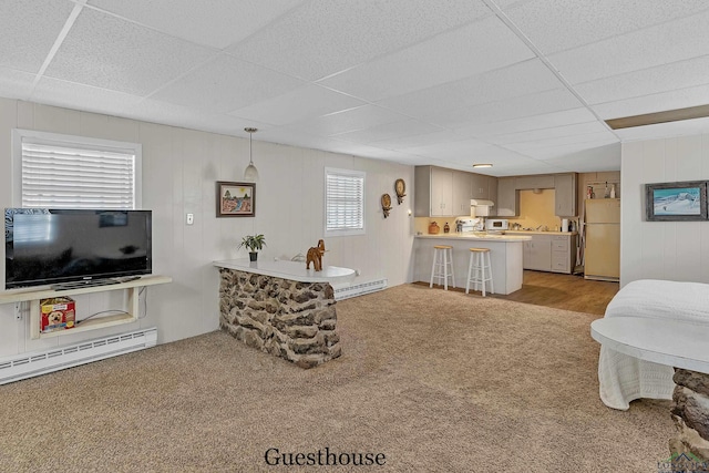 living room featuring a paneled ceiling, baseboard heating, and light colored carpet