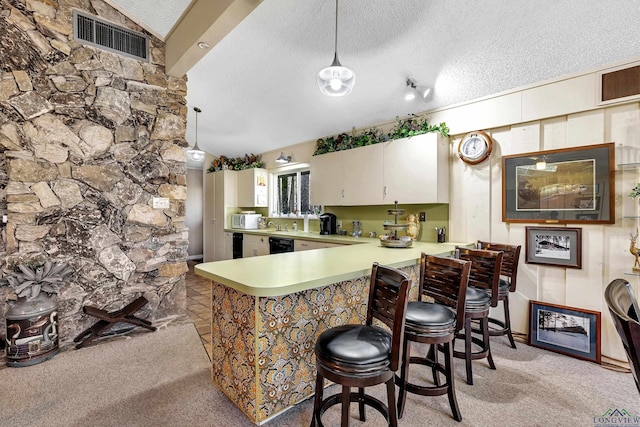 kitchen with kitchen peninsula, a textured ceiling, pendant lighting, a kitchen breakfast bar, and light carpet