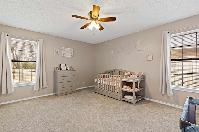 carpeted bedroom featuring multiple windows, baseboards, and a textured ceiling