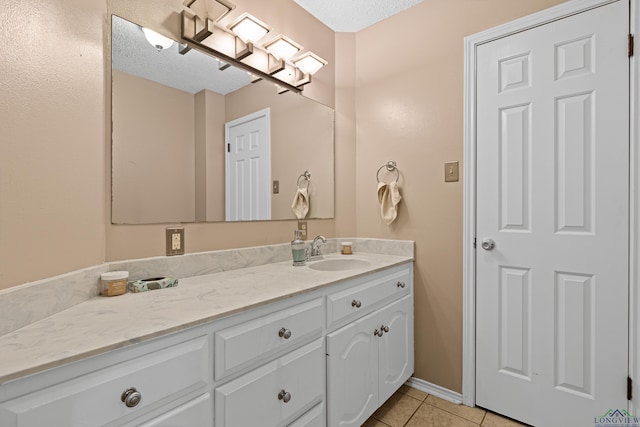 bathroom featuring baseboards, a textured ceiling, vanity, and tile patterned flooring