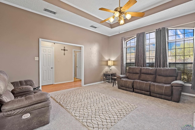 living area with visible vents, a raised ceiling, baseboards, and ceiling fan