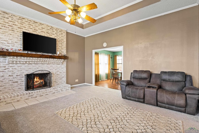 living room featuring carpet, a ceiling fan, a textured ceiling, crown molding, and a brick fireplace