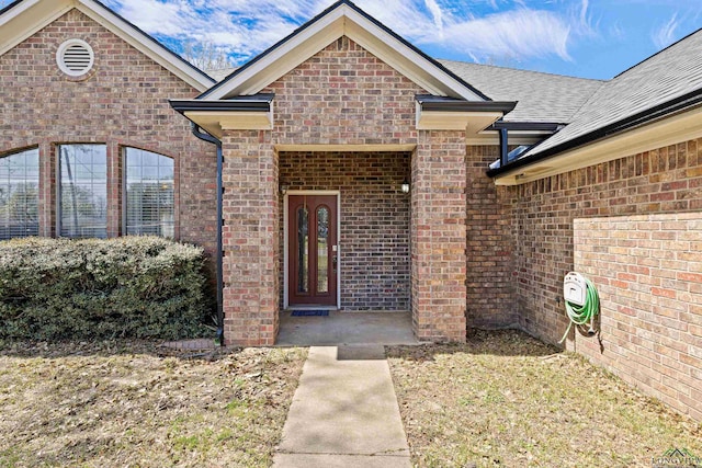 property entrance with brick siding and roof with shingles