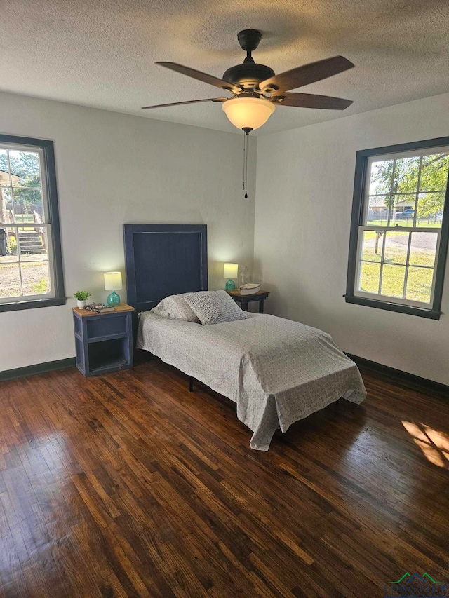 bedroom with a textured ceiling, dark hardwood / wood-style floors, and ceiling fan