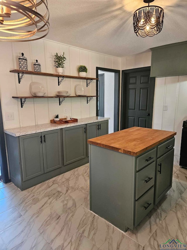 kitchen with a center island, butcher block countertops, a chandelier, a textured ceiling, and decorative light fixtures