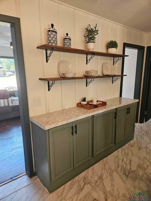 bar featuring light stone countertops, a textured ceiling, and green cabinetry