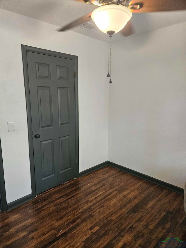 empty room featuring ceiling fan and dark wood-type flooring