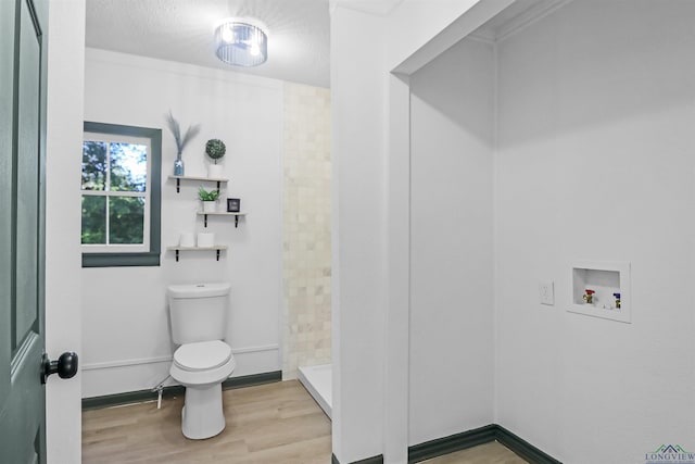 bathroom with hardwood / wood-style flooring, toilet, and walk in shower