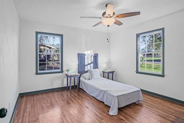 bedroom featuring a textured ceiling, ceiling fan, and dark wood-type flooring