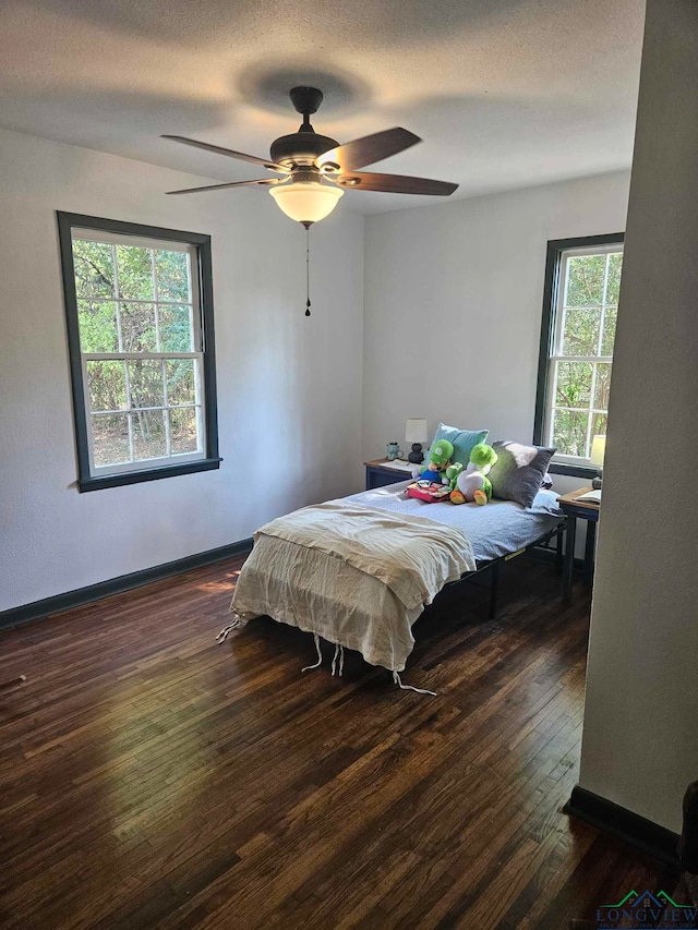 bedroom featuring multiple windows, a textured ceiling, dark hardwood / wood-style floors, and ceiling fan