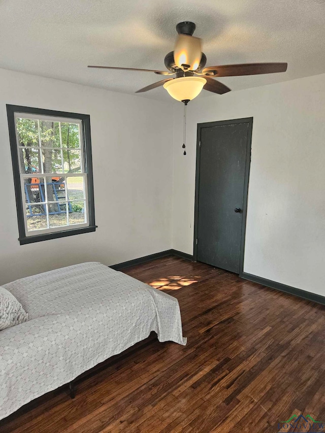 bedroom featuring a textured ceiling, ceiling fan, and dark hardwood / wood-style floors