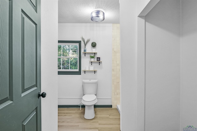 bathroom featuring hardwood / wood-style flooring, a textured ceiling, and toilet