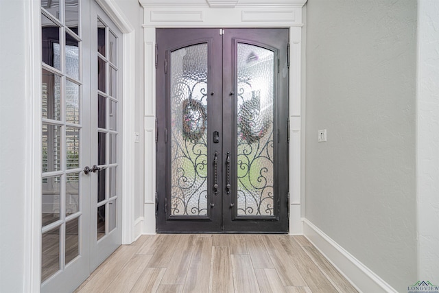 foyer entrance with french doors and light hardwood / wood-style flooring