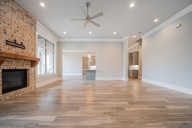 unfurnished living room with light hardwood / wood-style floors, ceiling fan, ornamental molding, and a brick fireplace