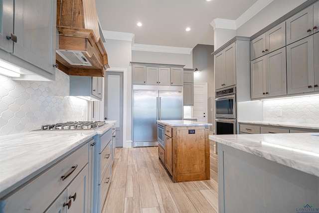 kitchen featuring backsplash, light stone countertops, crown molding, and stainless steel appliances