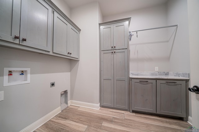 clothes washing area featuring cabinets, hookup for a washing machine, light wood-type flooring, and hookup for an electric dryer