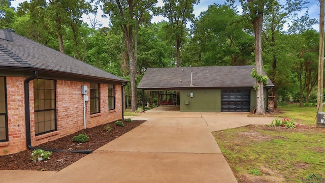 view of property exterior with brick siding, a shingled roof, and concrete driveway