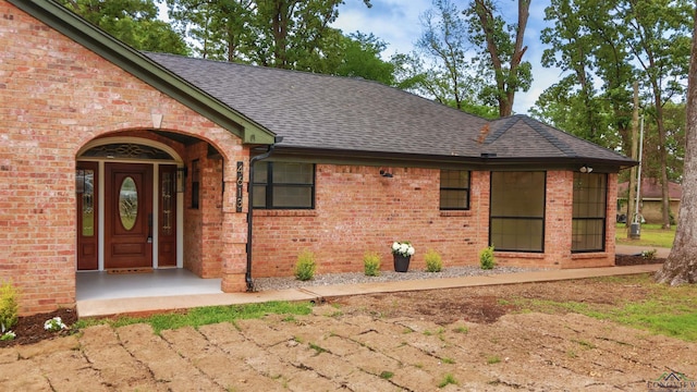 property entrance with brick siding and a shingled roof
