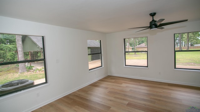 spare room with light wood-style floors, baseboards, and a ceiling fan