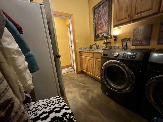 clothes washing area with cabinets, sink, and washing machine and clothes dryer