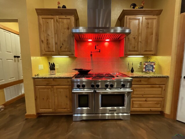 kitchen featuring double oven range, light stone counters, tasteful backsplash, and extractor fan