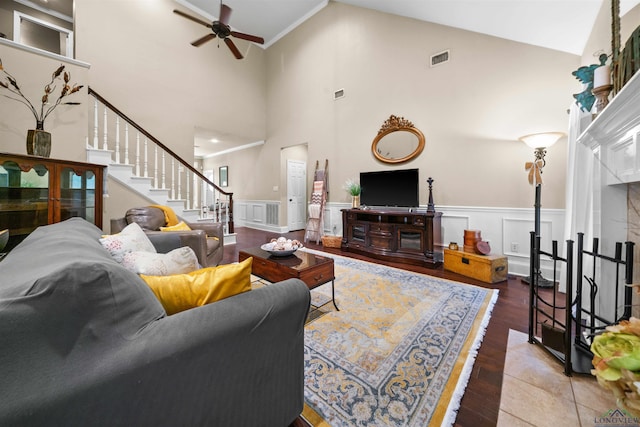 living room featuring a high ceiling, hardwood / wood-style flooring, ceiling fan, and ornamental molding