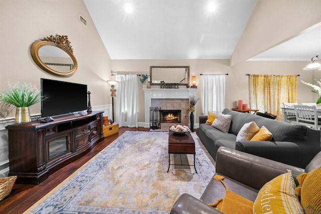 living room with a tile fireplace, dark hardwood / wood-style flooring, and lofted ceiling