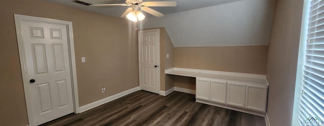 interior space with ceiling fan, dark wood-type flooring, built in desk, and vaulted ceiling