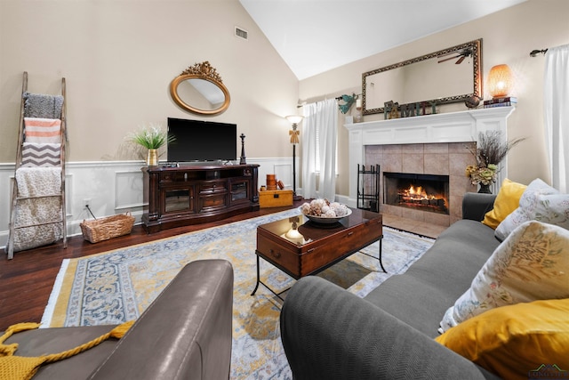 living room featuring dark hardwood / wood-style floors, lofted ceiling, and a tile fireplace