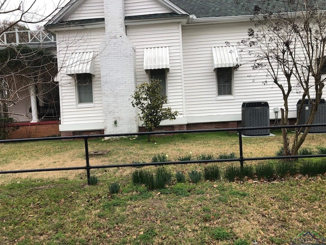 view of side of property with central AC and a yard