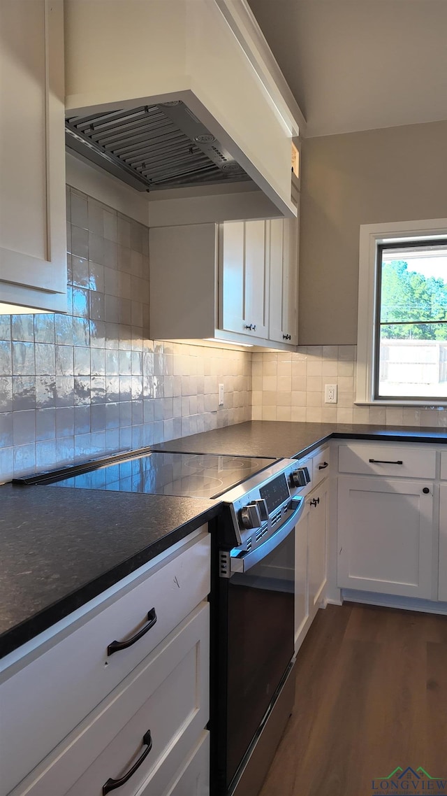 kitchen featuring white cabinets, dark wood finished floors, dark countertops, premium range hood, and backsplash