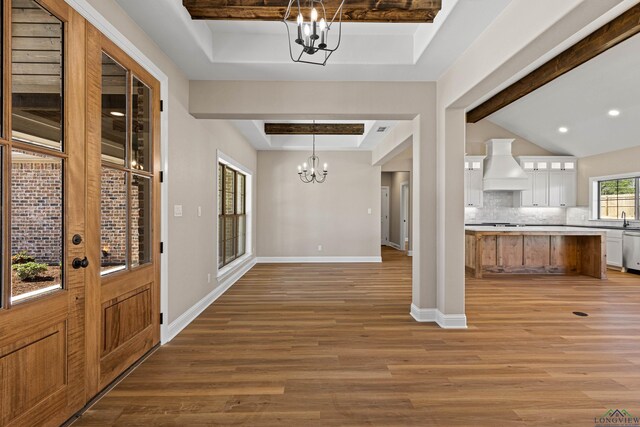 169 Andres Ln, Kilgore, TX 75662 - foyer entrance featuring a tray ceiling, baseboards, light wood finished floors, and an inviting chandelier
