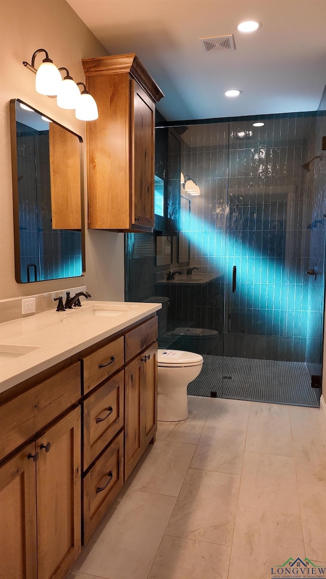 bathroom featuring toilet, a sink, visible vents, a shower stall, and double vanity