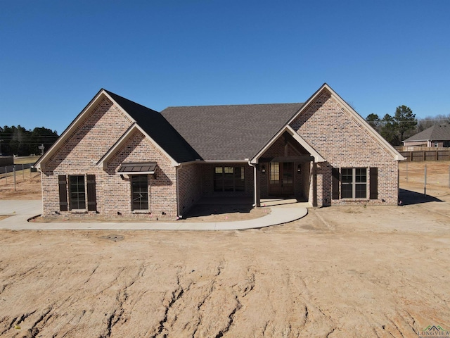 view of front facade featuring brick siding and fence