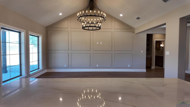 unfurnished dining area featuring lofted ceiling, an inviting chandelier, visible vents, and a decorative wall