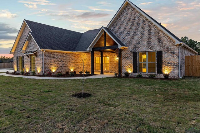 169 Andres Ln, Kilgore, TX 75662 - view of front facade with brick siding, fence, roof with shingles, and a front yard