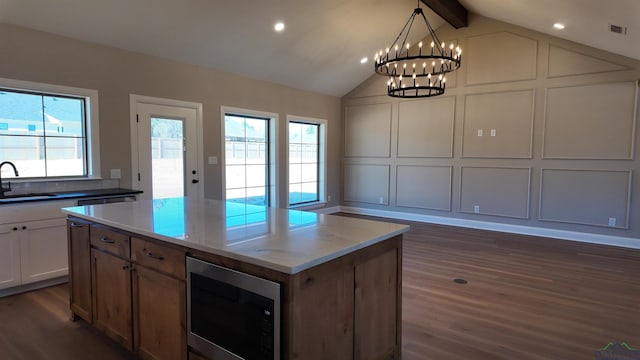 kitchen featuring plenty of natural light, built in microwave, a decorative wall, and a sink