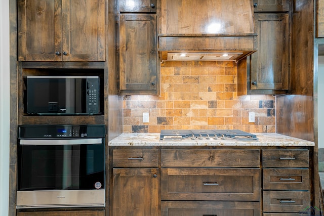 kitchen with backsplash, dark brown cabinetry, light stone countertops, and appliances with stainless steel finishes