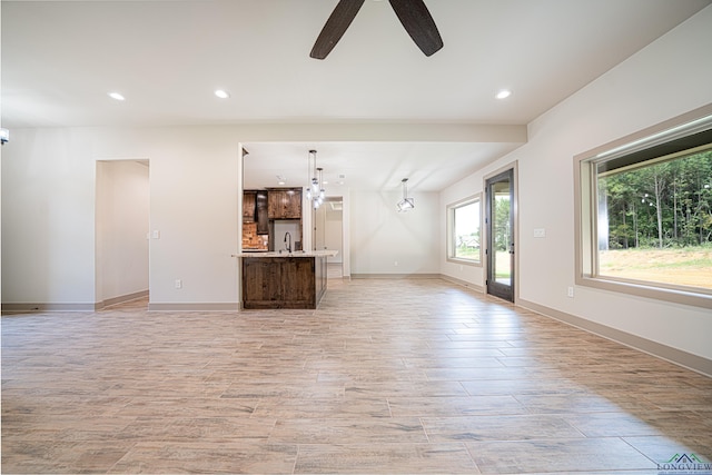 unfurnished living room with ceiling fan and sink