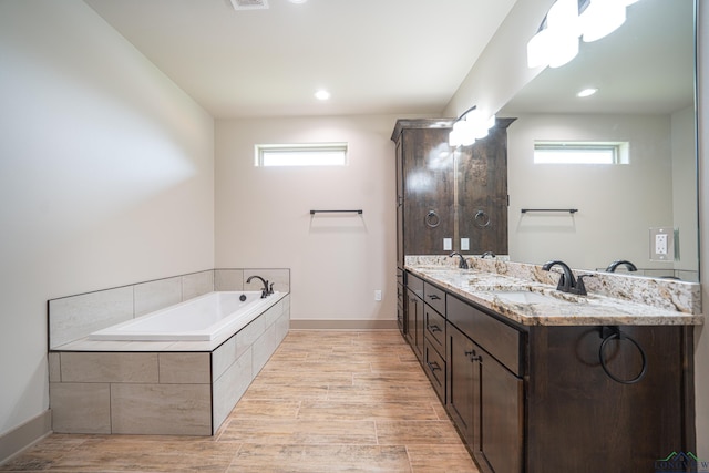 bathroom featuring vanity, tiled bath, and plenty of natural light