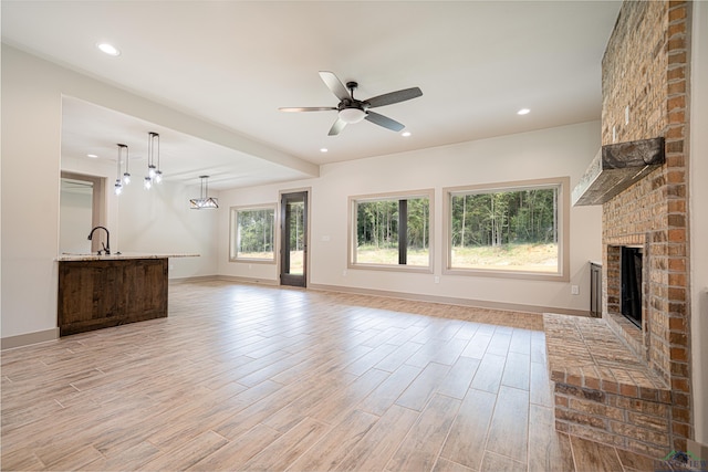 unfurnished living room featuring ceiling fan, a fireplace, and sink