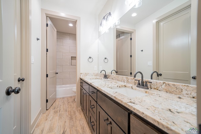 full bathroom with hardwood / wood-style floors, vanity, toilet, and tiled shower / bath