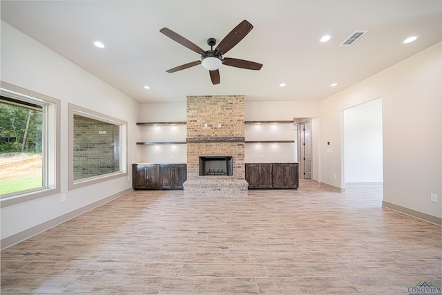 unfurnished living room featuring a brick fireplace and ceiling fan