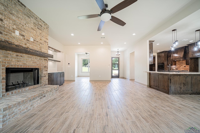 unfurnished living room featuring ceiling fan, sink, and a fireplace