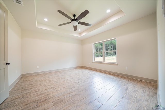 empty room with a raised ceiling and ceiling fan