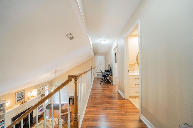 corridor with lofted ceiling and hardwood / wood-style flooring