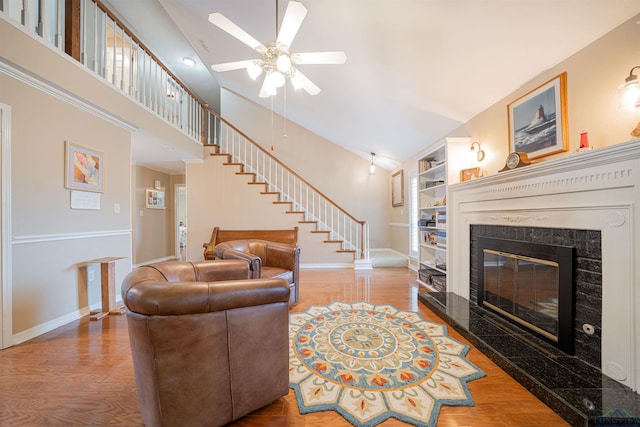 living room featuring ceiling fan, a high end fireplace, wood-type flooring, and built in features