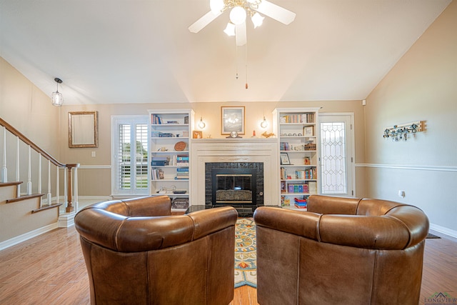 living room with ceiling fan, lofted ceiling, built in shelves, and hardwood / wood-style flooring