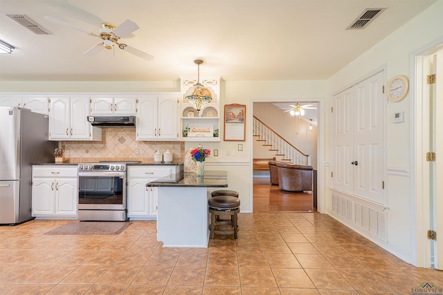 kitchen with a kitchen breakfast bar, white cabinets, stainless steel appliances, and tasteful backsplash